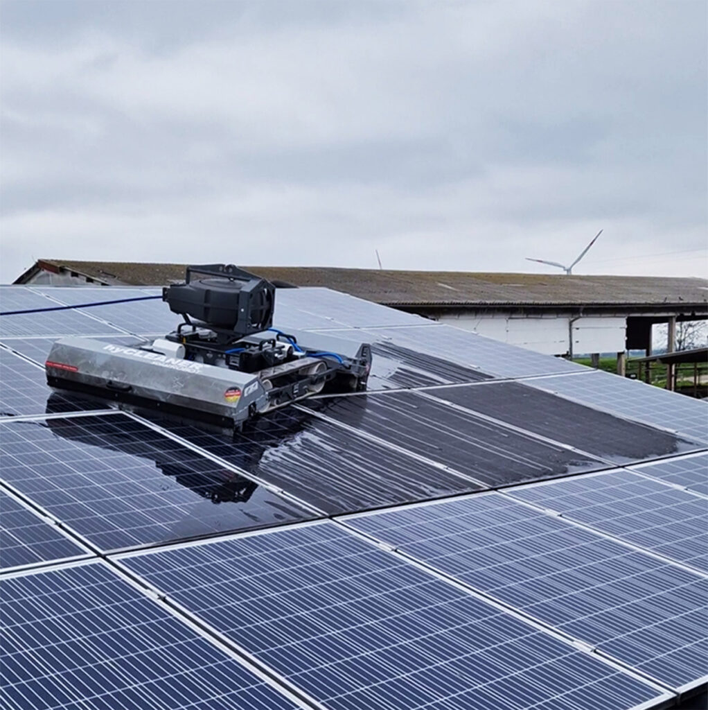 Solarreinigungsroboter bei der Solarreinigung. Man sieht den Unterschied zwischen den glänzenden, gereinigten Solarmodulen und der matten Fläche, die noch gereinigt werden muss durch SoluShine Solarreinigung.